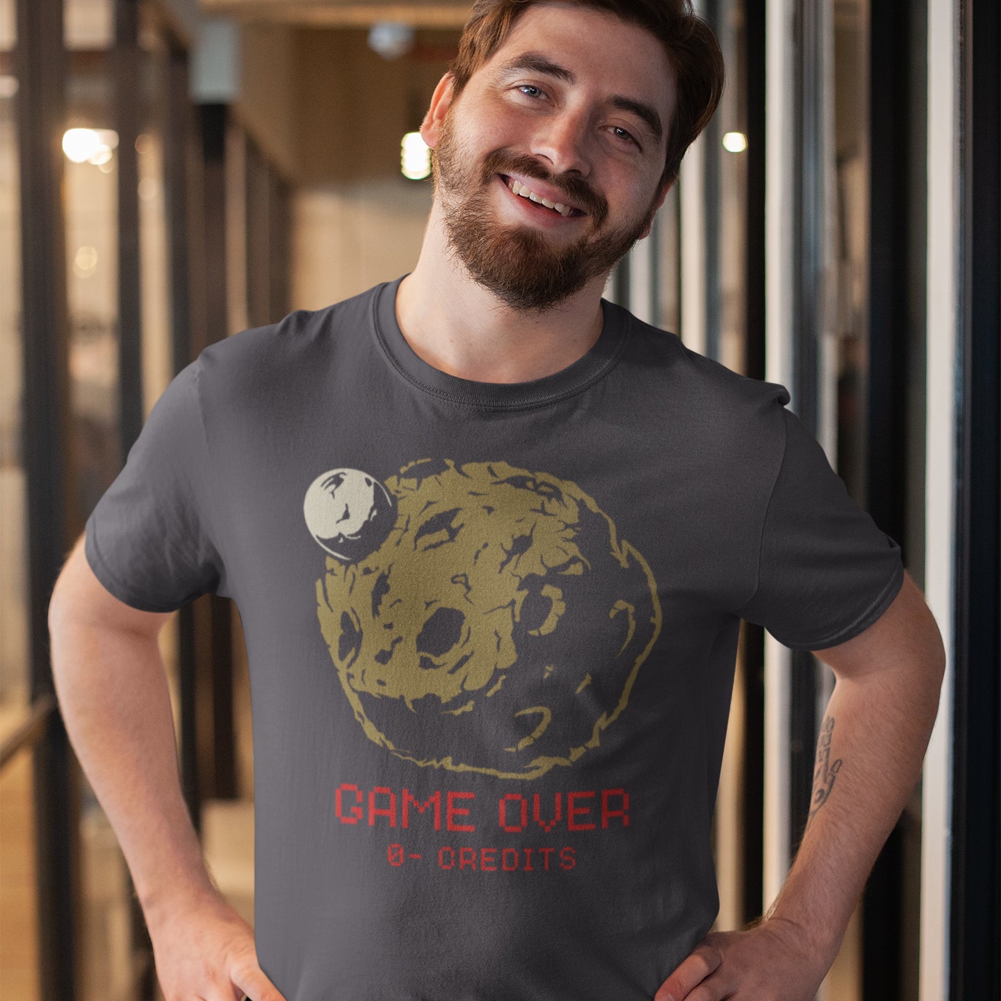 Man wearing a t-shirt with a graphic design and text, standing indoors. A save the earth t shirt design suggesting we are not taking our environmental issues seriously enough, and are treating it all like a game. The problem is that when this game ends, it ends. Planet and environmental concern for gamers and everybody else. Made from 100% organic ring-spun cotton, this save the earth t shirt is unisex, high-quality, super comfy, and best of all, eco-friendly.