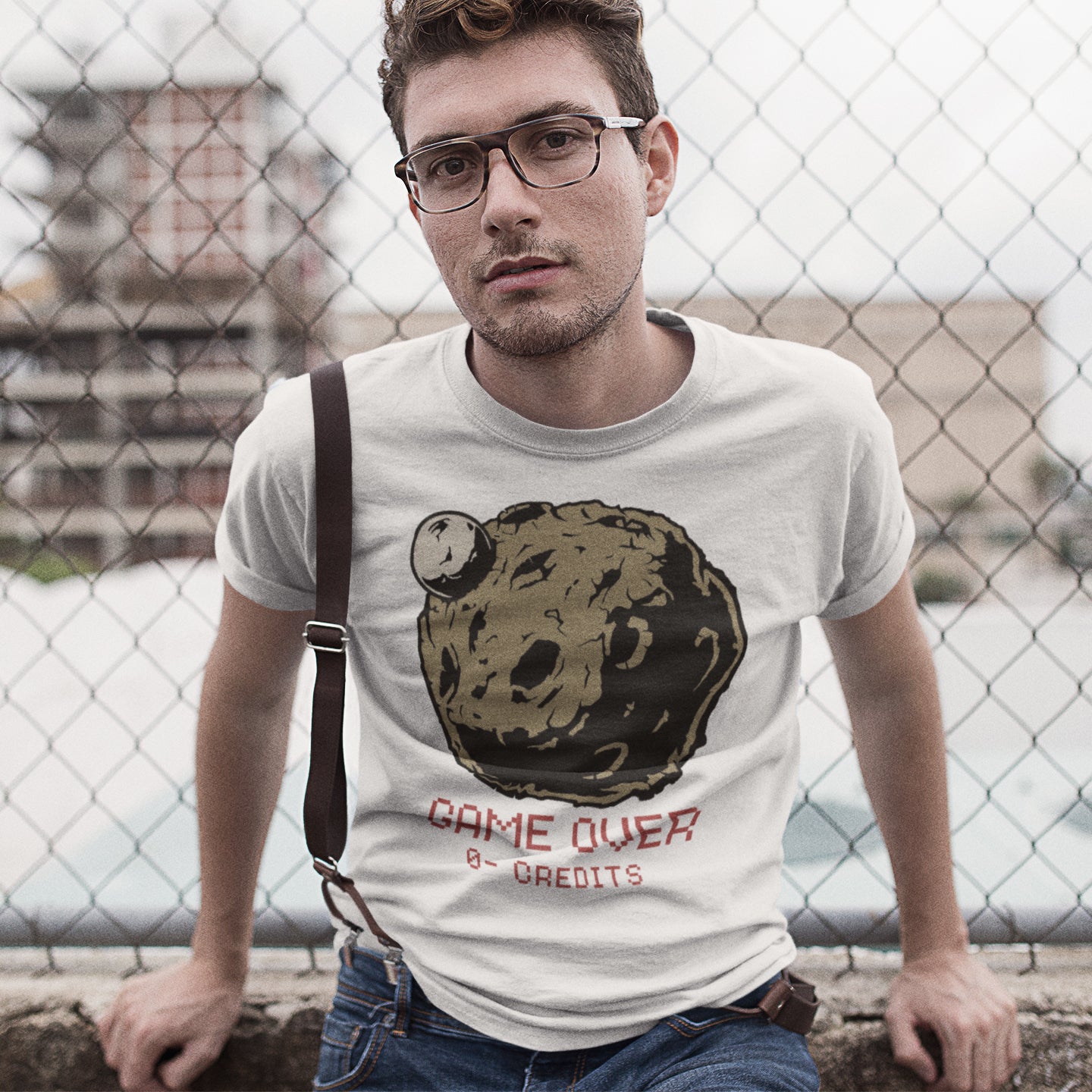 Man wearing a t-shirt with a graphic design and text, standing in front of a chain-link fence. A save the earth t shirt design suggesting we are not taking our environmental issues seriously enough, and are treating it all like a game. The problem is that when this game ends, it ends. Planet and environmental concern for gamers and everybody else. Made from 100% organic ring-spun cotton, this save the earth t shirt is unisex, high-quality, super comfy, and best of all, eco-friendly.