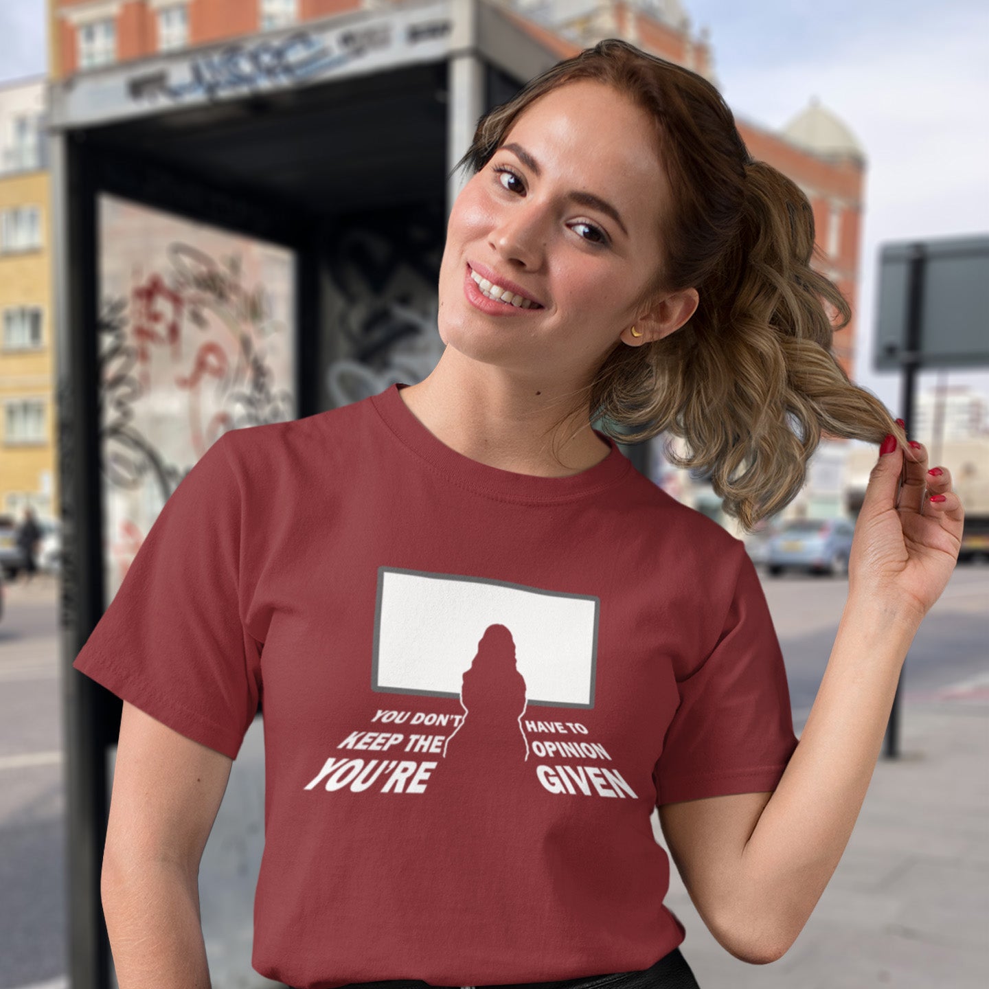 Woman wearing a burgundy t-shirt with a graphic design on a city street background. A non conformist t shirt design to promote self awareness. In a age of external influence. especially from mass media, lets not forget that you still own the right to investigate and form your own opinion. A design to promote independent thought and the need to think outside the box. Made from 100% organic ring-spun cotton, this self worth t shirt is unisex, high quality, super comfy, and best of all, eco-friendly.