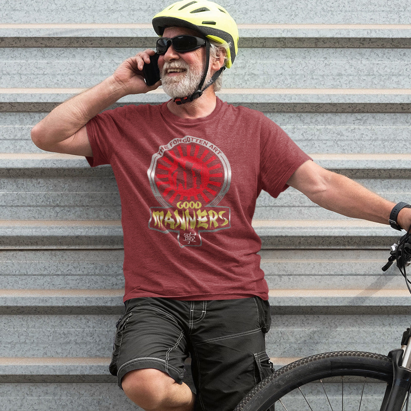 Man with a bicycle talking on a phone, wearing a helmet and sunglasses, against a grey metal staircase. A sign of the times t shirt design suggesting that good manners are dying out. A dig at modern social awareness and lack of politeness.  Made from 100% organic ring-spun cotton, this social awareness t shirt is unisex, high-quality, super comfy, and best of all, eco-friendly.