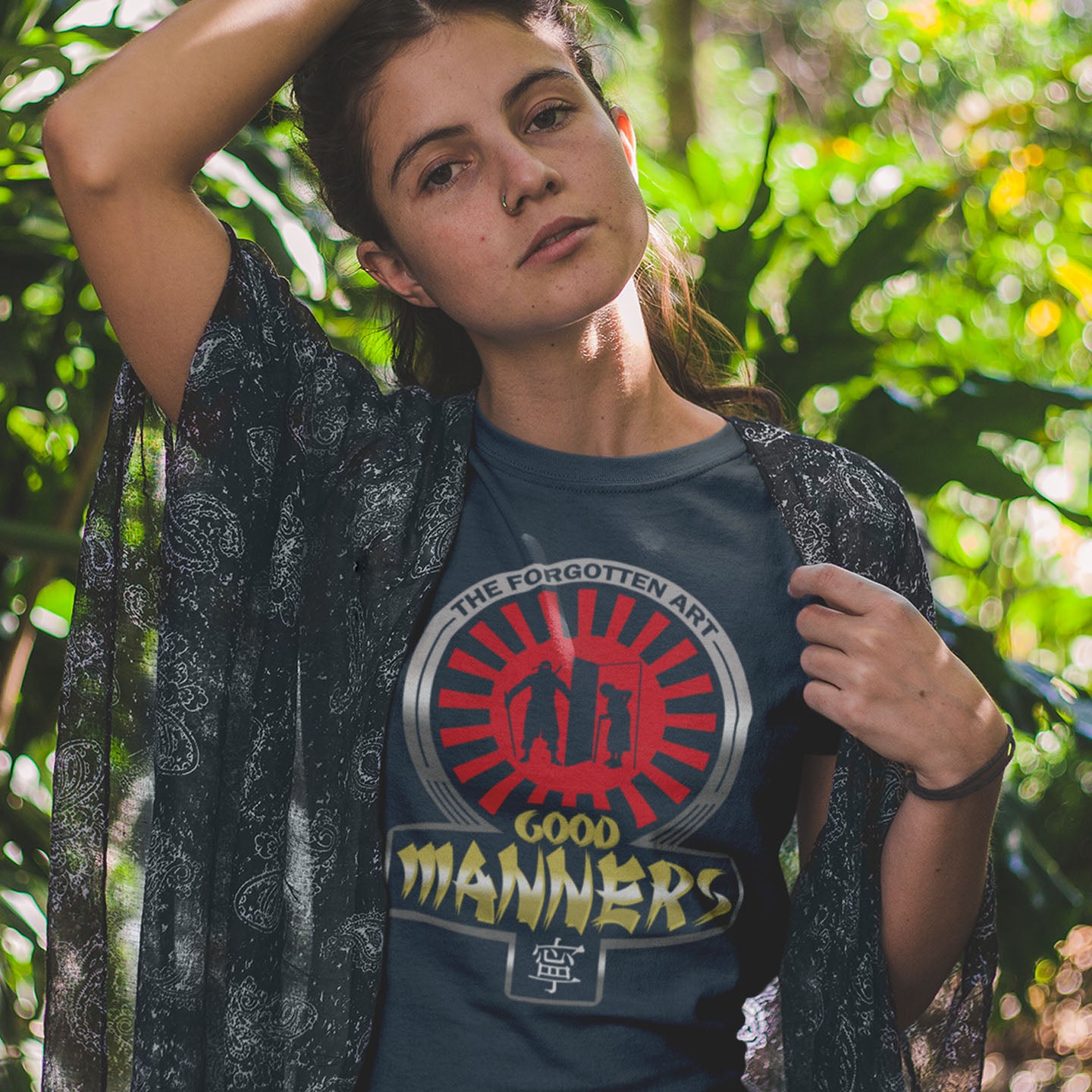 Woman wearing a t-shirt with a graphic design in a forest setting. A sarcastic and satirical t-shirt design suggesting that good manners are dying out. A dig at modern social awareness and lack of politeness. Made from 100% organic ring-spun cotton, this social awareness t-shirt is unisex, high-quality, super comfy, and best of all, eco-friendly.