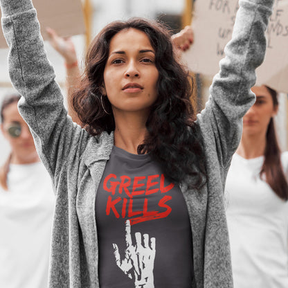 A woman holding up a placard at a rally wearing an anthracite  crew neck t-shirt with a hand writing "GREED KILLS" in blood red. 