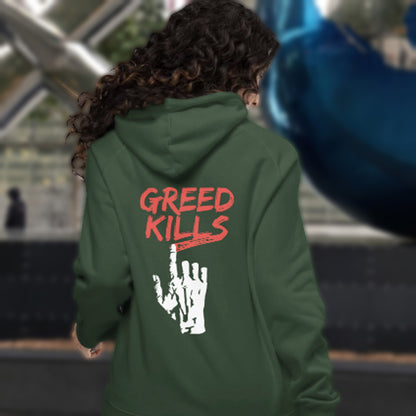Person wearing a bottle green hoodie with 'GREED KILLS' text on the back, standing in an outdoor setting. An anti-capitalism hoodie design focusing on greed. It's the slow-creeping, strong-holding virus that has been with us since the beginning of time, yet we still can't find a cure. Comfortable and practical. It's extra soft and has a convenient front pouch pocket. Made from organic cotton and recycled polyester, this non conformist hoodie is a great eco-friendly choice for the anti-capitalist.