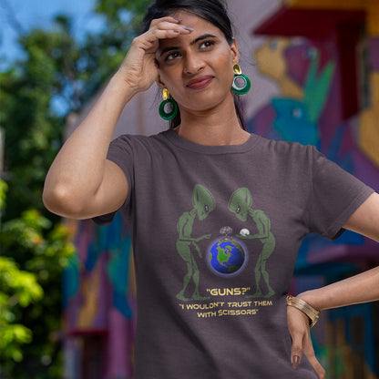 Woman wearing a t-shirt with alien graphic and text, standing in front of a colourful mural. This funny alien t shirt highlights our over use of weaponry. With our lust for guns we must look out of control from an alien view point. No wonder they don't openly reveal themselves to us. Made from 100% organic ring-spun cotton, this counter culture t shirt is unisex, high-quality, super comfy, and best of all, eco-friendly.