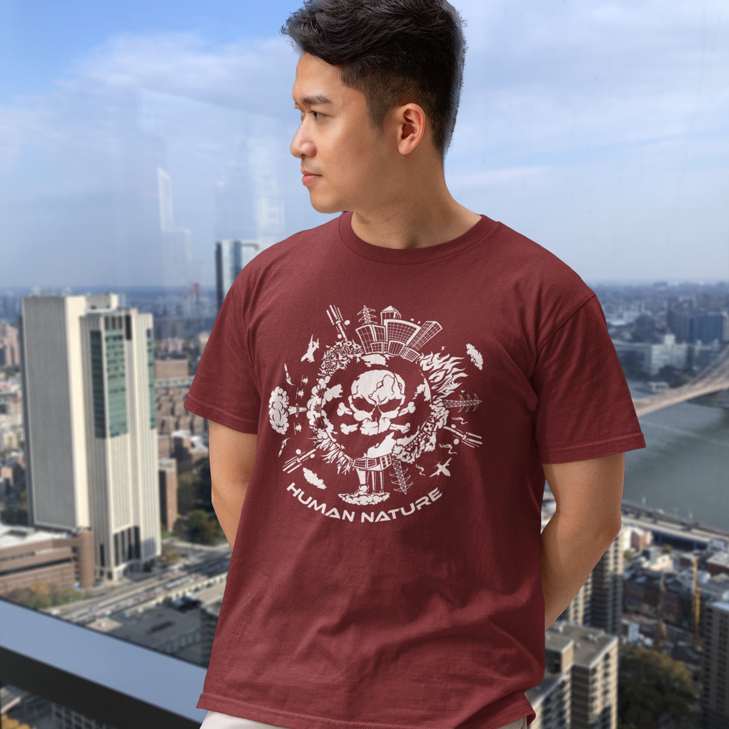 Person wearing a burgundy t-shirt with a graphic design and 'Human Nature' text, standing against an urban skyline. This save the world t shirt claims human nature is nowhere near as good as mother nature. It's not only about environmental issues. How do we save the planet from human nature. Made from 100% organic ring-spun cotton, this save the earth t shirt is unisex, high-quality, super comfy, and best of all, eco-friendly.