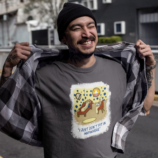 A man wearing n anthracite grey graphic t-shirt featuring a white graphic print on the front. The graphic shows a cartoon smartphone with a human on a lead talking to another smartphone, with the text 'HOW ADORABLE, DOES IT DO TRICKS?' above and 'DAARLING, IT DOES ANYTHING I TELL IT TO!' below.