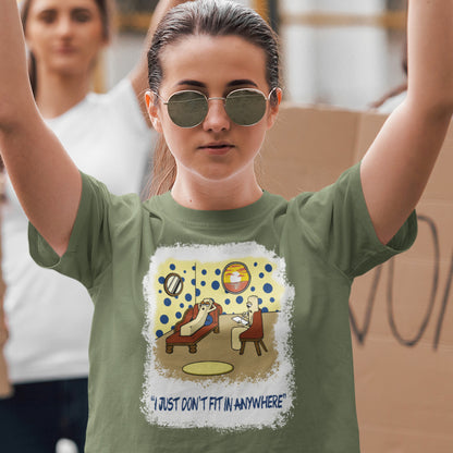 Person wearing a khaki t-shirt with a graphic design and text, standing with arms raised. A funny cartoon t-shirt for all you 'square pegs in round holes' out there. You are not alone. This unique design is ideal for anyone who thinks outside the box. Made from 100% organic ring-spun cotton, this witty cartoon t-shirt is unisex, high-quality, super comfy, and best of all, eco-friendly.