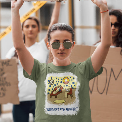 Person wearing a khaki t-shirt with a graphic design and text, holding up a cardboard sign. A funny non conformist t shirt for all you 'square pegs in round holes' out there. You are not alone. This unique design is ideal for anyone who thinks outside the box. Made from 100% organic ring-spun cotton, this sarcastic slogan t shirt is unisex, high-quality, super comfy, and best of all, eco-friendly.