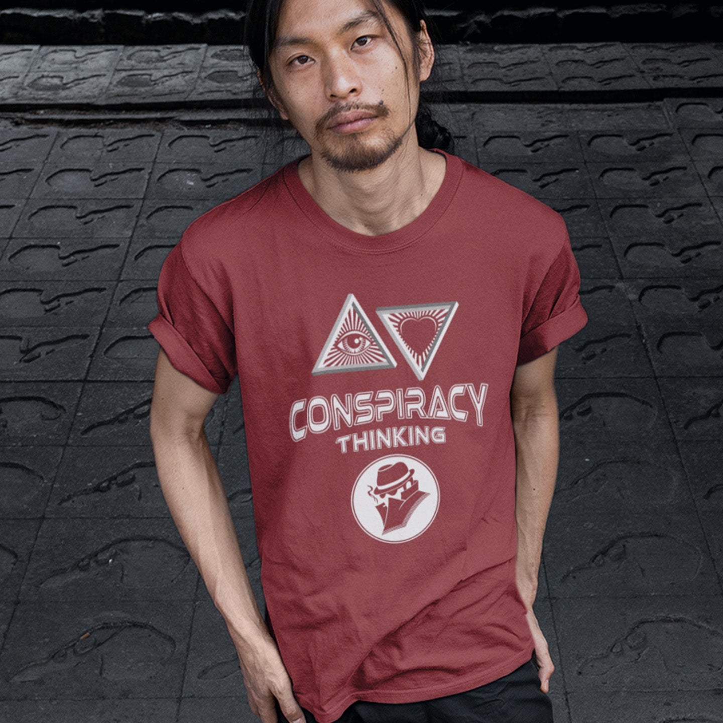 Person wearing a burgundy t-shirt with 'Conspiracy Thinking' design against a dark textured background. A cryptic conspiracy theory t-shirt design for all of those conspiracy theory lovers out there who know it's more than a theory, it's a way of life. From Alien advocates or bigfoot believers to Cabal conspiracy theorists, an original design for all. Made from 100% organic ring-spun cotton, this conspiracy theory t-shirt is unisex, high-quality, super comfy, and best of all, eco-friendly.