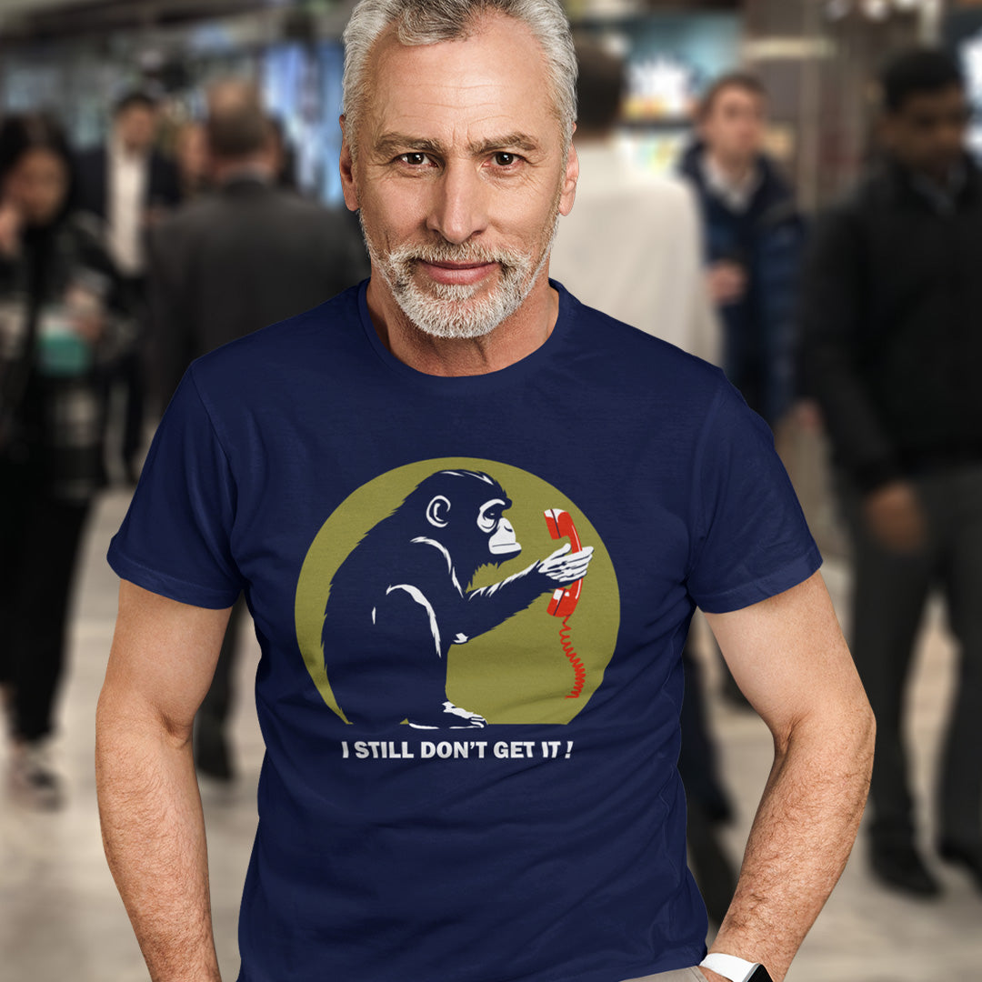 Man wearing a French navy blue t-shirt with a graphic design and text in a busy indoor setting. This anti smart phone abuse t-shirt design highlights the human obsession with smart phones and how strange it must look to an ape. An outsiders view of a world glued to mobile phones. Made from 100% organic ring-spun cotton, this anti mobile phone abuse t-shirt is unisex, high-quality, super comfy, and best of all, eco-friendly.