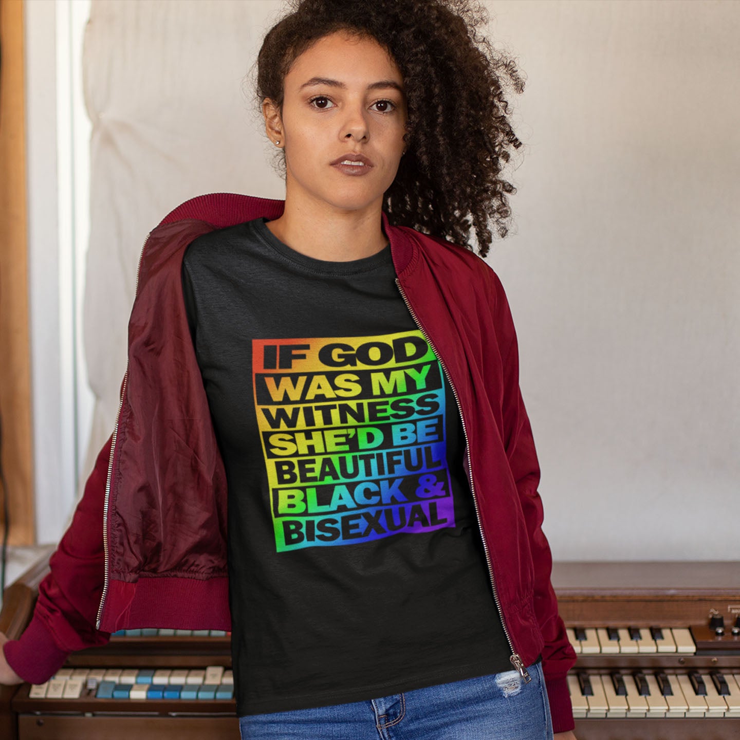 Person wearing a black t-shirt with colourful text in a room with a piano. A liberal thinkers t-shirt design. LGBTQ+ friendly and anti-racism in one. If there is a God she's probably more open minded than people give her credit for. Made from 100% organic ring-spun cotton, this alternative view t-shirt is unisex, high-quality, super comfy, and best of all, eco-friendly.