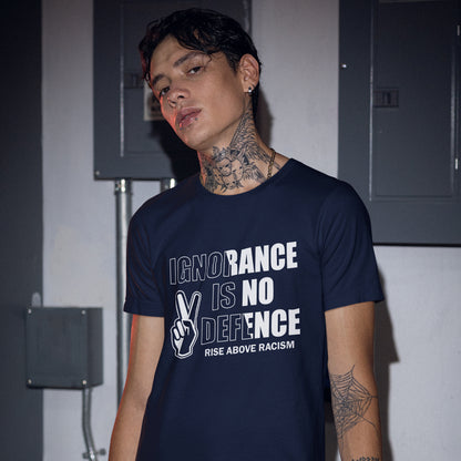 A man wearing a French navy blue graphic t-shirt with the text 'IGNORANCE IS NO DEFENCE RISE ABOVE RACISM' and a peace sign hand graphic, standing in front of grey electrical cabinets.