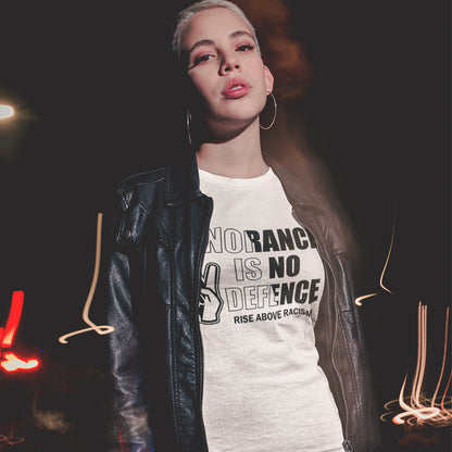 A person wearing a white graphic T-shirt with black text reading 'NO RACISM IS NO DEFENCE. RISE ABOVE RACISM.