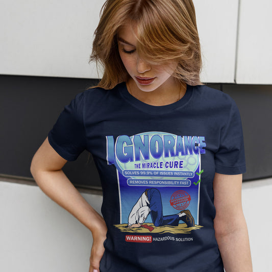 Woman standing against a wall looking down and wearing a French navy T-shirt  with "IGNORANCE THE MIRICLE CURE" design.