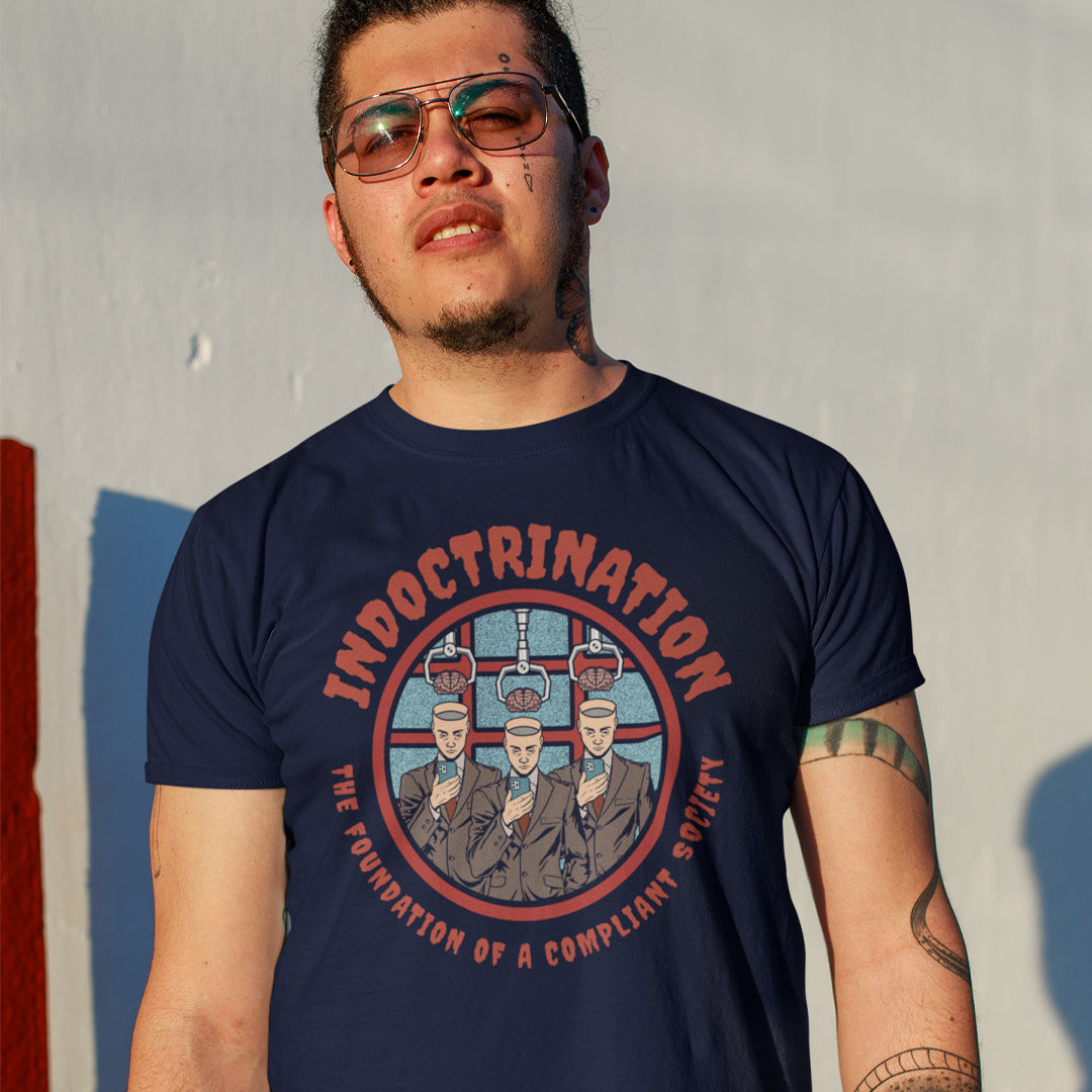 Man wearing a navy blue t-shirt with a graphic design and text. A conspiracy theory t shirt exposing indoctrination as the foundation of modern society. What we believe before we realise we are being lied to shapes our lives until we take back our own opinions. Made from 100% organic ring-spun cotton, this non conformist t shirt is unisex, high quality, super comfy, and best of all, eco-friendly.