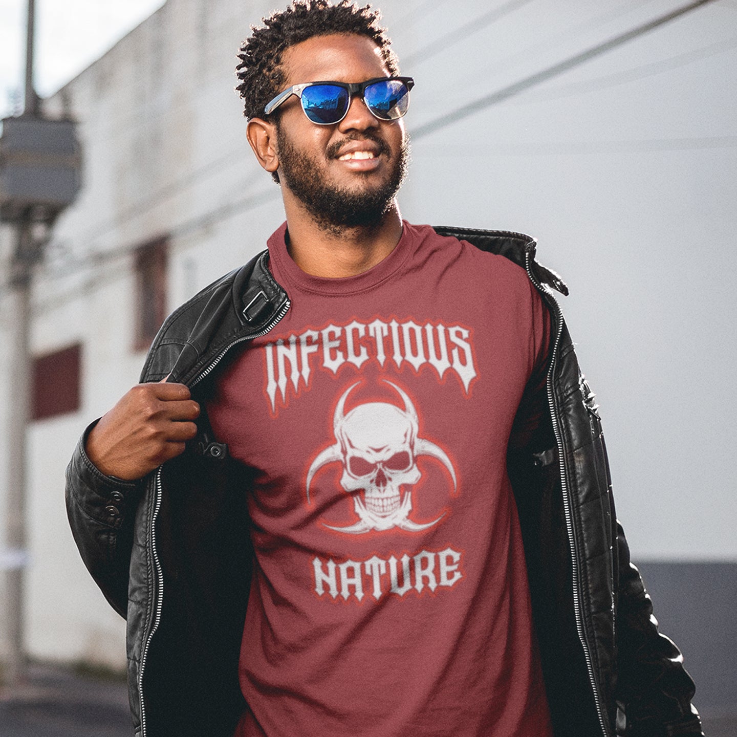 Man wearing a burgundy t-shirt with 'Infectious Nature' design and sunglasses, standing outdoors. This urban art t shirt design has a double meaning. You can have an infectious nature but it's also within our nature, as a race, to infect. Made from 100% organic ring-spun cotton, this social awareness t shirt is unisex, high-quality, super comfy, and best of all, eco-friendly.