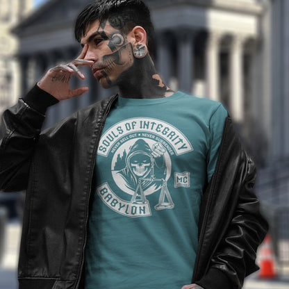 Man wearing a teal t-shirt with a graphic design and text, standing outdoors. A social awareness t shirt promoting ethics and morality. A spoof motorcycle club design for people who still have integrity. This design satirically representing how few people are left with a moral conscience in a corrupt world, or as the Rastafarians call it, BABYLON. Made from 100% organic ring-spun cotton, these social issues t shirts are unisex, high-quality, super comfy, and best of all, eco-friendly.