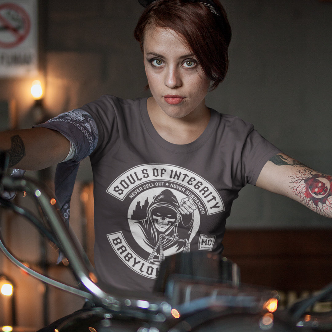 Person wearing a 'Souls of Integrity Babylon' t-shirt in a dimly lit room. A social awareness t shirt promoting ethics and morality. A spoof motorcycle club design for people who still have integrity. This design satirically representing how few people are left with a moral conscience in a corrupt world, or as the Rastafarians call it, BABYLON. Made from 100% organic ring-spun cotton, these social issues t shirts are unisex, high-quality, super comfy, and best of all, eco-friendly.