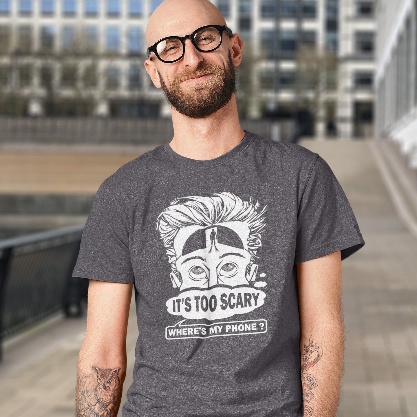 Man wearing an anthracite t-shirt with a graphic design and text, standing outdoors. An anti-mobile phone abuse t-shirt highlighting the effects on the mind of smart phone over use in the place of thinking. A view of how mobile phones have taken over thinking and left us with dark unexplored corridors in our minds. Made from 100% organic ring-spun cotton, this social awareness t-shirt is unisex, high-quality, super comfy, and best of all, eco-friendly.