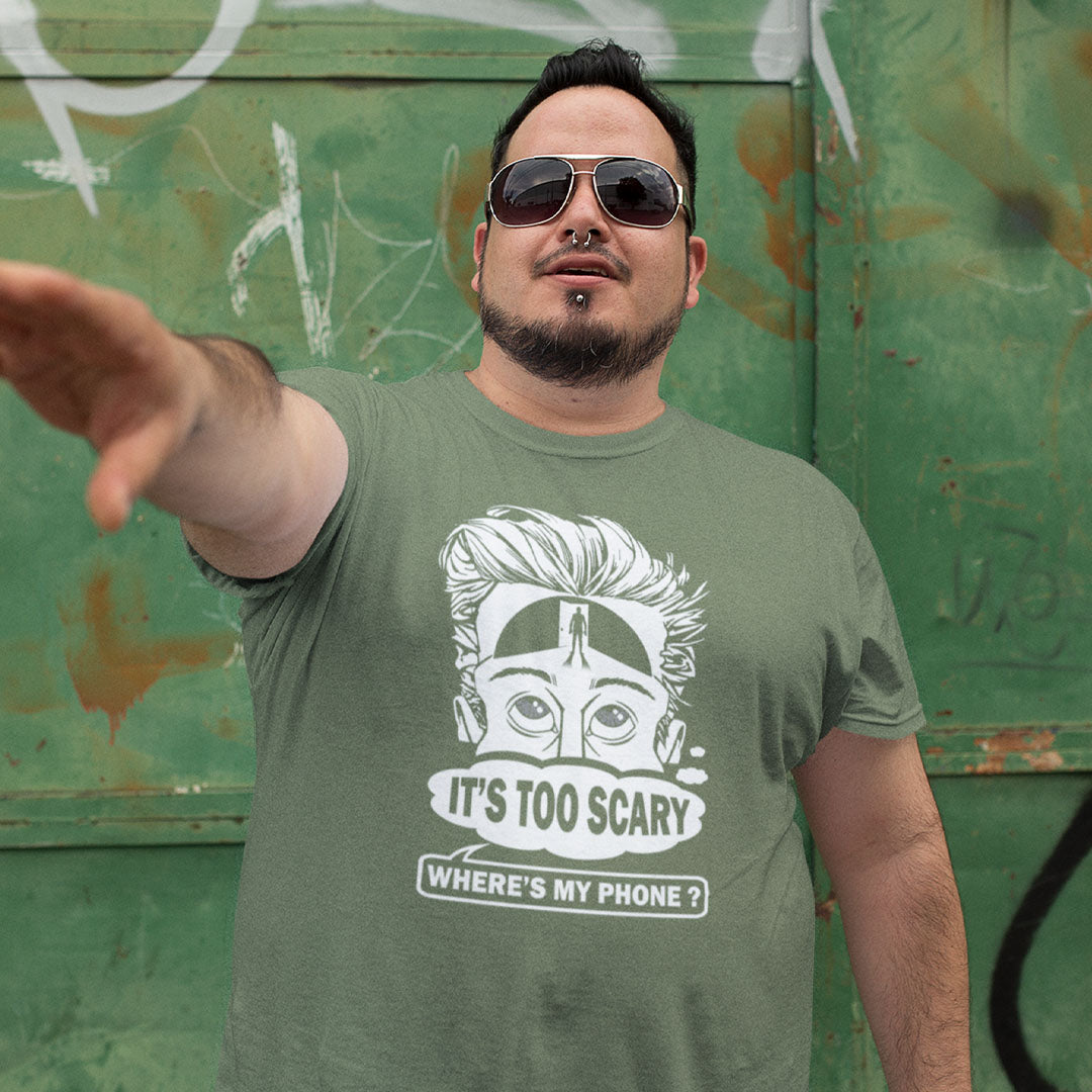 Man wearing a khaki t-shirt with a graphic design and text, standing in front of a green wall with graffiti. An anti mobile phone abuse t-shirt highlighting the effects on the mind of smart phone over use in the place of thinking. A view of how mobile phones have taken over thinking and left us with dark unexplored corridors in our minds. Made from 100% organic ring-spun cotton, this social awareness t-shirt is unisex, high-quality, super comfy, and best of all, eco-friendly.
