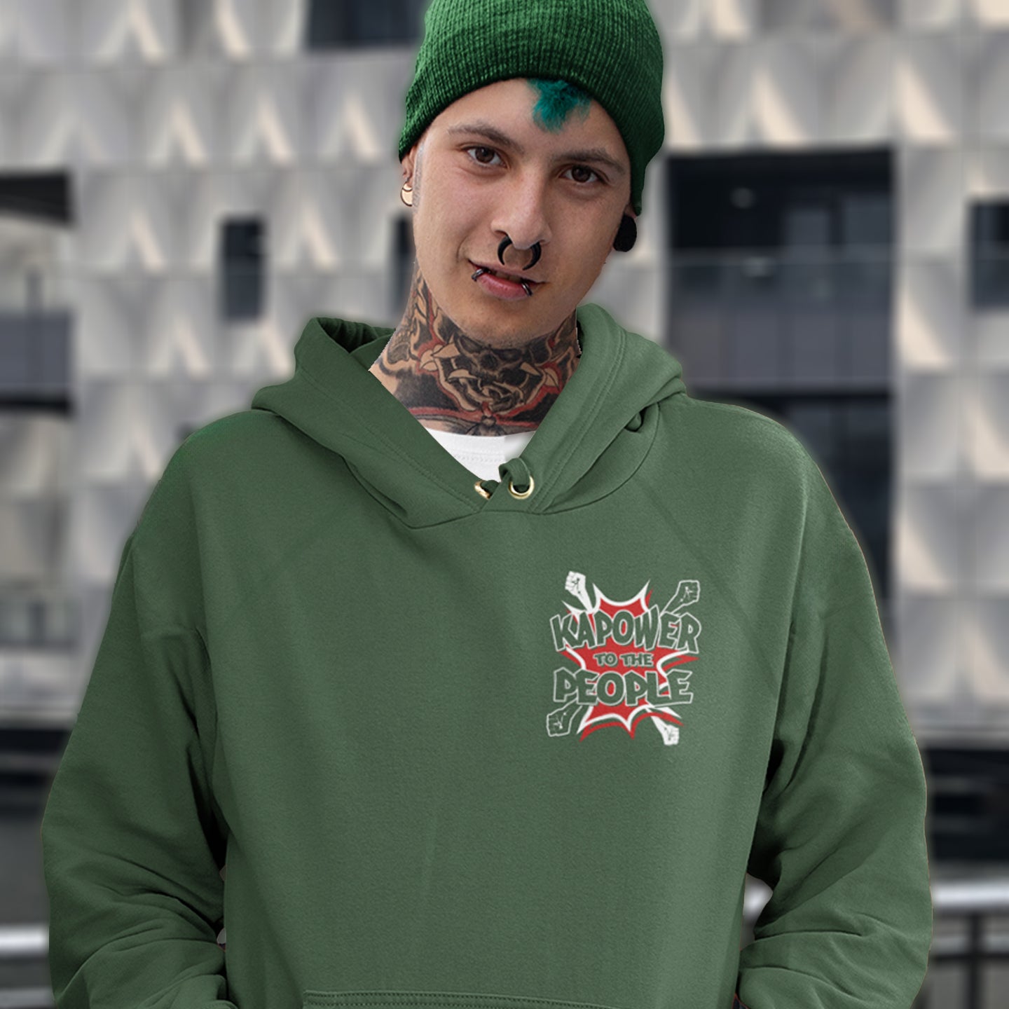 Person wearing a bottle green hoodie with a logo and text, standing against a patterned wall. An anti-government hoodie design that packs a punch with this humorous play on the slogan 'Power to the people', with a comic book twist. Support true democracy with this witty political message. Comfortable and practical. It's extra soft and has a convenient front pouch pocket. Made from organic cotton and recycled polyester, this social awareness hoodie is a great eco-friendly choice.