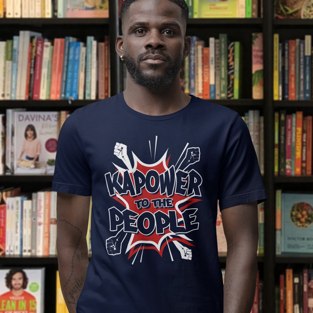 Man wearing a navy blue t-shirt with 'Kapower to the People' design in front of a bookshelf. This anti government t shirt packs a punch with this humorous play on the slogan 'Power to the people', with a comic book twist. Support true democracy with this funny political message. Made from 100% organic ring-spun cotton, this unisex non conformist t shirt is a total must-have. It's high-quality, super comfy, and best of all, eco-friendly