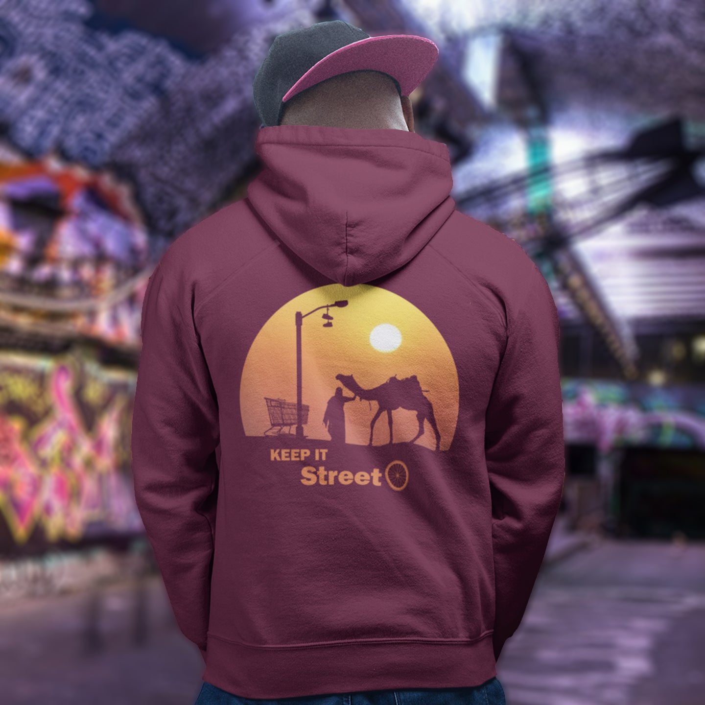 Person wearing a burgundy hoodie with a sunset design and text, standing in an urban setting. This street art inspired hoodie design represents inner city street life as a culture of it's own.  Wherever you are in the world, may the street be with you. Comfortable and practical. It's extra soft and has a convenient front pouch pocket. Made from organic cotton and recycled polyester, this street art hoodie is a great eco-friendly choice.