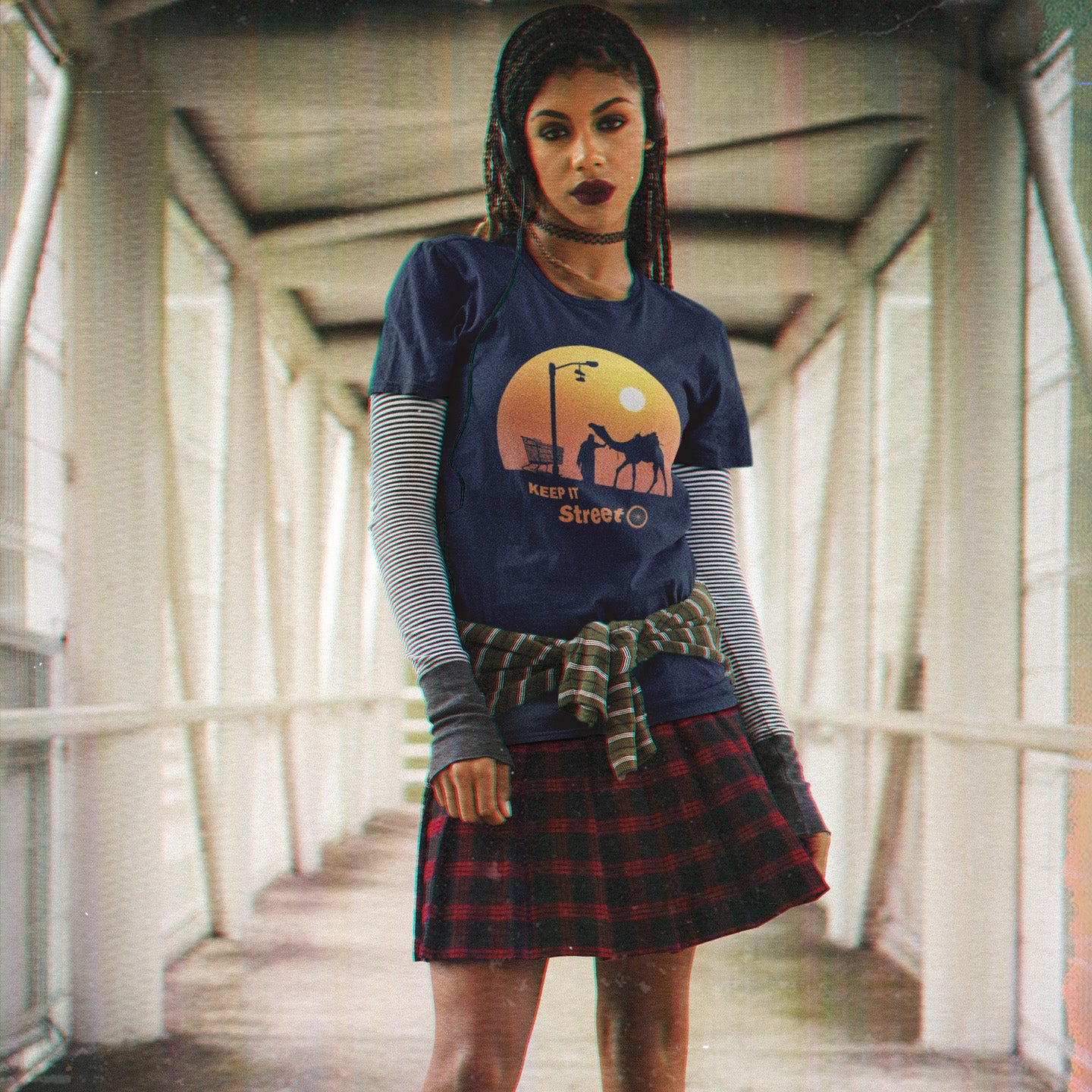 Woman wearing a blue t-shirt with a graphic design and plaid skirt in an urban setting. This humorous, underground stencil art represents inner city street life as a culture of it's own. There is a ground level reality mixed with trustworthy honestly at street level in towns and cities across the planet. Wherever you are in the world, may the street be with you. Made from 100% organic ring-spun cotton, this street art t-shirt is unisex, high-quality, super comfy, and best of all, eco-friendly.