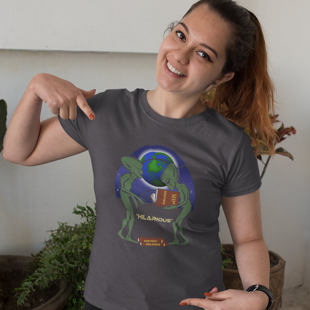 Woman wearing a dark gey t-shirt with a graphic design, pointing to it. This funny alien t shirt suggest we are being lied to about our history and the aliens know the truth. A design for alien loving conspiracy theorists. Have the aliens had more influence in our lives than we are lead to believe ? Made from 100% organic ring-spun cotton, these cool sci fi t shirts are unisex, high-quality, super comfy, and best of all, eco-friendly.