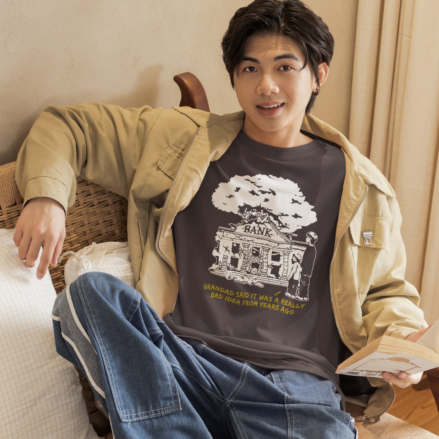 Man sitting on a couch wearing a graphic t-shirt with a design and text. An anti capitalism t shirt with a wishful message. A thought provoking future where money and banking are a dark memory and our children have something more natural to look forward to. Made from 100% organic ring-spun cotton, this utopian graffiti stencil t-shirt is unisex, high-quality, super comfy, and best of all, eco-friendly.