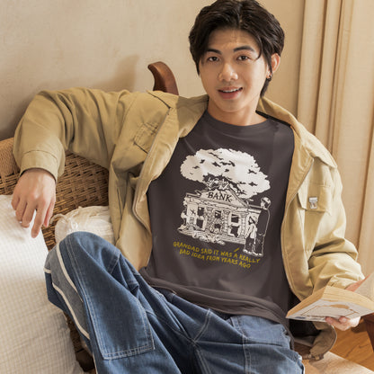 Man sitting on a couch wearing a graphic t-shirt with a design and text. An anti capitalism t shirt with a wishful message. A thought provoking future where money and banking are a dark memory and our children have something more natural to look forward to. Made from 100% organic ring-spun cotton, this utopian graffiti stencil t-shirt is unisex, high-quality, super comfy, and best of all, eco-friendly.