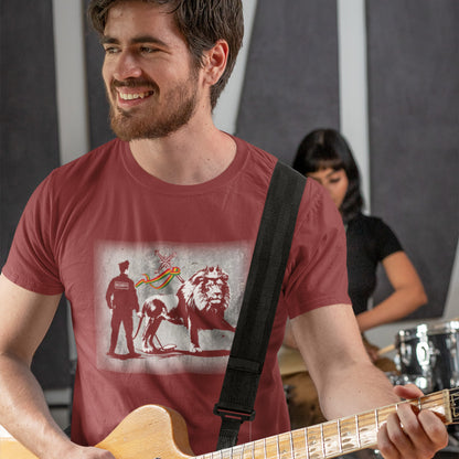 A man smiling and playing guitar, wearing a burgundy short sleeved crew neck t-shirt with a graffiti stencil design of a security guard checking the underside of the Lion of Judah for explosives.