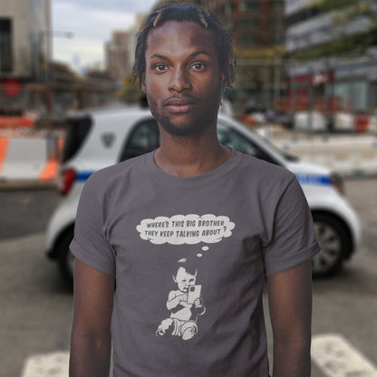 Person wearing a t-shirt with a graphic and text, standing in an urban setting. A witty conspiracy theory t-shirt questioning the existence of a controlling 'Big Brother' watching over us. This unique design in stencil art illustrates the sweet mind of a child and a lesson in how to take things literally. Big Brother is everywhere and nowhere. Made from 100% organic ring-spun cotton, this Banksy style conspiracy theory t-shirt is unisex, high-quality, super comfy, and best of all, eco-friendly.