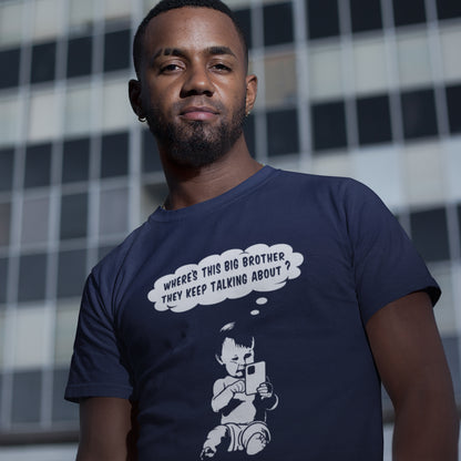 Man wearing a French navy blue t-shirt with a graphic design and text, standing against a chequered wall. A funny conspiracy theory t shirt questioning the existence of a controlling 'Big Brother' watching over us. This unique design in stencil art illustrates the sweet mind of a child and a lesson in how to take things literally. Big Brother is everywhere and nowhere. Made from 100% organic ring-spun cotton, this stencil graffiti t shirt is unisex, high-quality, super comfy, and best of all, eco-friendly.