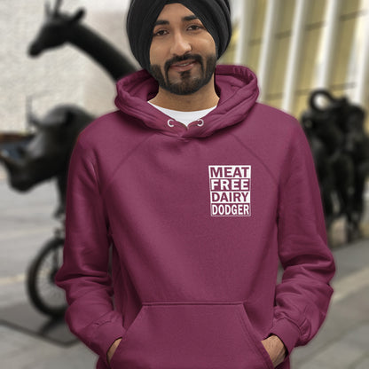 Person wearing a burgundy hoodie with 'MEAT FREE DAIRY DODGER' text, standing in an urban setting. This plant based vegan hoodie promotes a witty alternative to the 'non-dairy' label. Never mind 'plant based' as a new label for vegan . This is straight off the streets of East London. Comfortable and practical. It's extra soft and has a convenient front pouch pocket. Made from organic cotton and recycled polyester, this meat free hoodie design is a great eco-friendly choice.