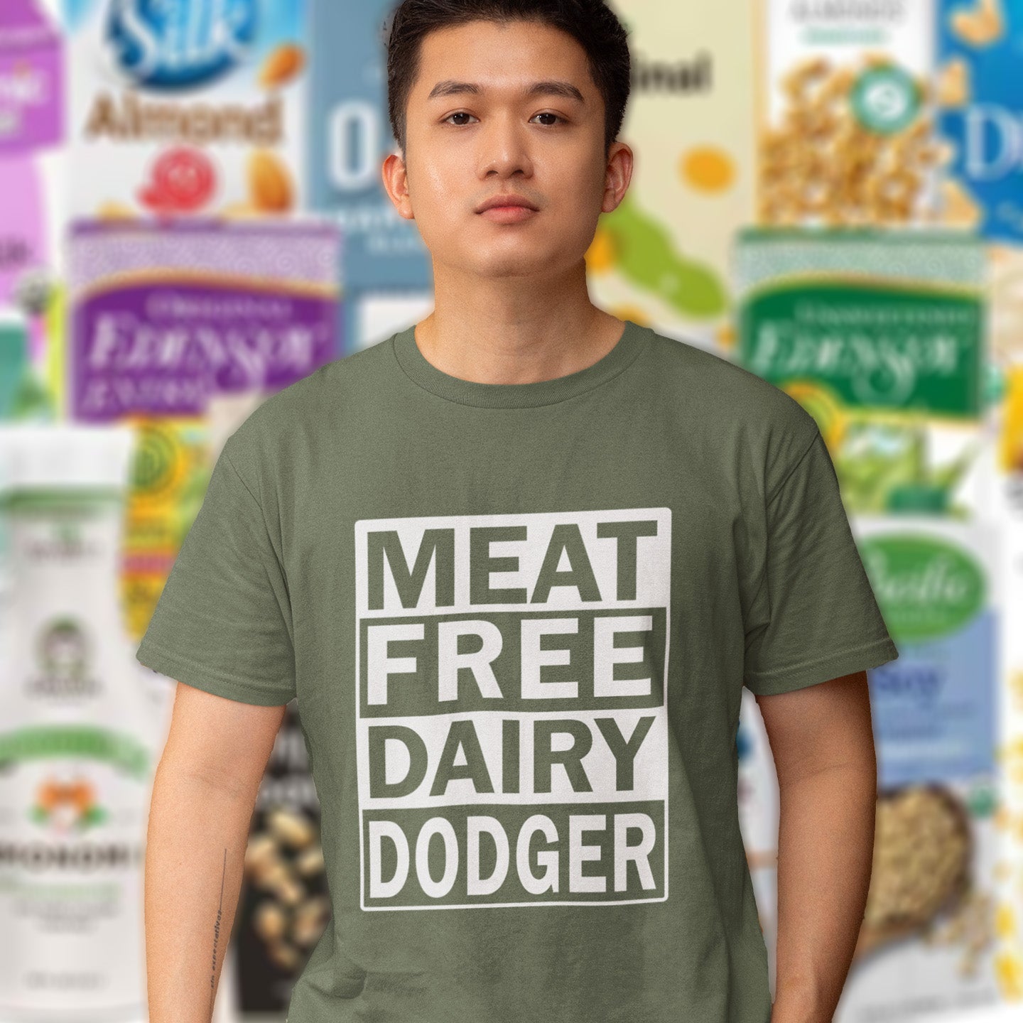 Person wearing a khaki t-shirt with 'MEAT FREE DAIRY DODGER' text in front of cereal boxes. A vegan meat free t shirt promoting a witty alternative to the 'vegan' label. Never mind 'plant based' as a new label for vegan . This is straight off the streets of East London. Made from 100% organic ring-spun cotton, this vegan dairy free t shirt is unisex, high-quality, super comfy, and best of all, eco-friendly.