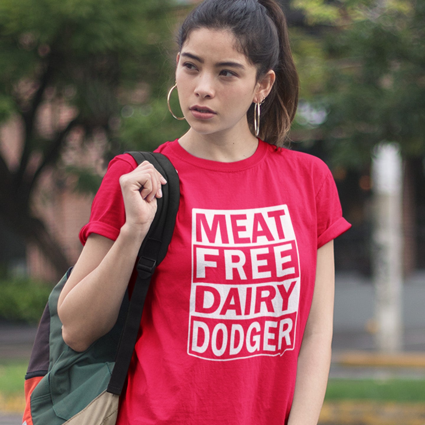 Person wearing a red t-shirt with 'MEAT FREE DAIRY DODGER' text outdoors. A vegan meat free t shirt promoting a witty alternative to the 'vegan' label. Never mind 'plant based' as a new label for vegan . This is straight off the streets of East London. Made from 100% organic ring-spun cotton, this vegan dairy free t shirt is unisex, high-quality, super comfy, and best of all, eco-friendly.
