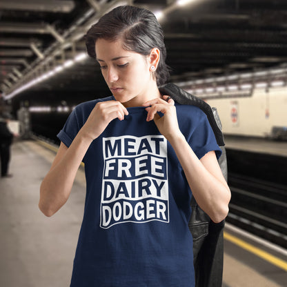 A woman wearing a French navy blue t-shirt with 'MEAT FREE DAIRY DODGER' printed in white block letters, standing on a train station platform with a black jacket slouched over her shoulder.