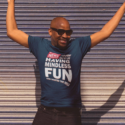 Man wearing a French navy blue t-shirt with humorous text, standing against a corrugated metal wall. A witty quotes t shirt with a front page life philosophy. When you look back over your life, How are you going to see it ? Made from 100% organic ring-spun cotton, these clever slogan t shirts are unisex, high-quality, super comfy, and best of all, eco-friendly.
