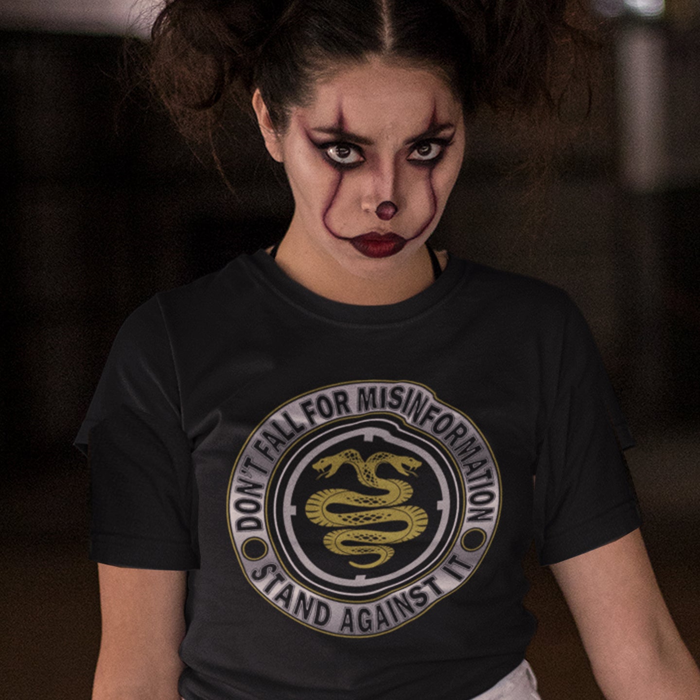 Person wearing a black t-shirt with a snake emblem and text, against a dark background. A non conformist t shirt design. Call it SPIN, LIES or GASLIGHTING , It's all misinformation. There's a lot of it about these days and most of it seems to be coming from above. Made from 100% organic ring-spun cotton, this social awareness t-shirt is unisex, high-quality, super comfy, and best of all, eco-friendly.