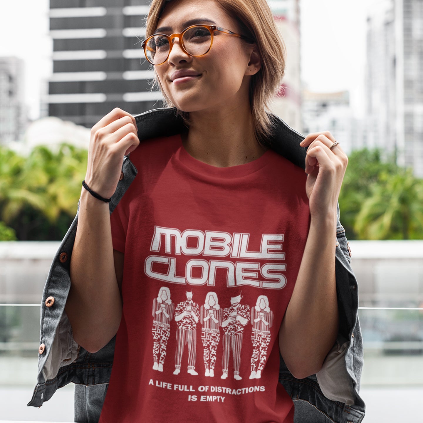 Person wearing a red t-shirt with 'MOBILE CLONES' design outdoors. Smart phones are taking the imagination out of life. Soon we will all look the same, think the same, and all buy the same un-needed online products, or has that already happened ? Made from 100% organic ring-spun cotton, this anti-consumerism t-shirt is unisex, high-quality, super comfy, and best of all, eco-friendly.