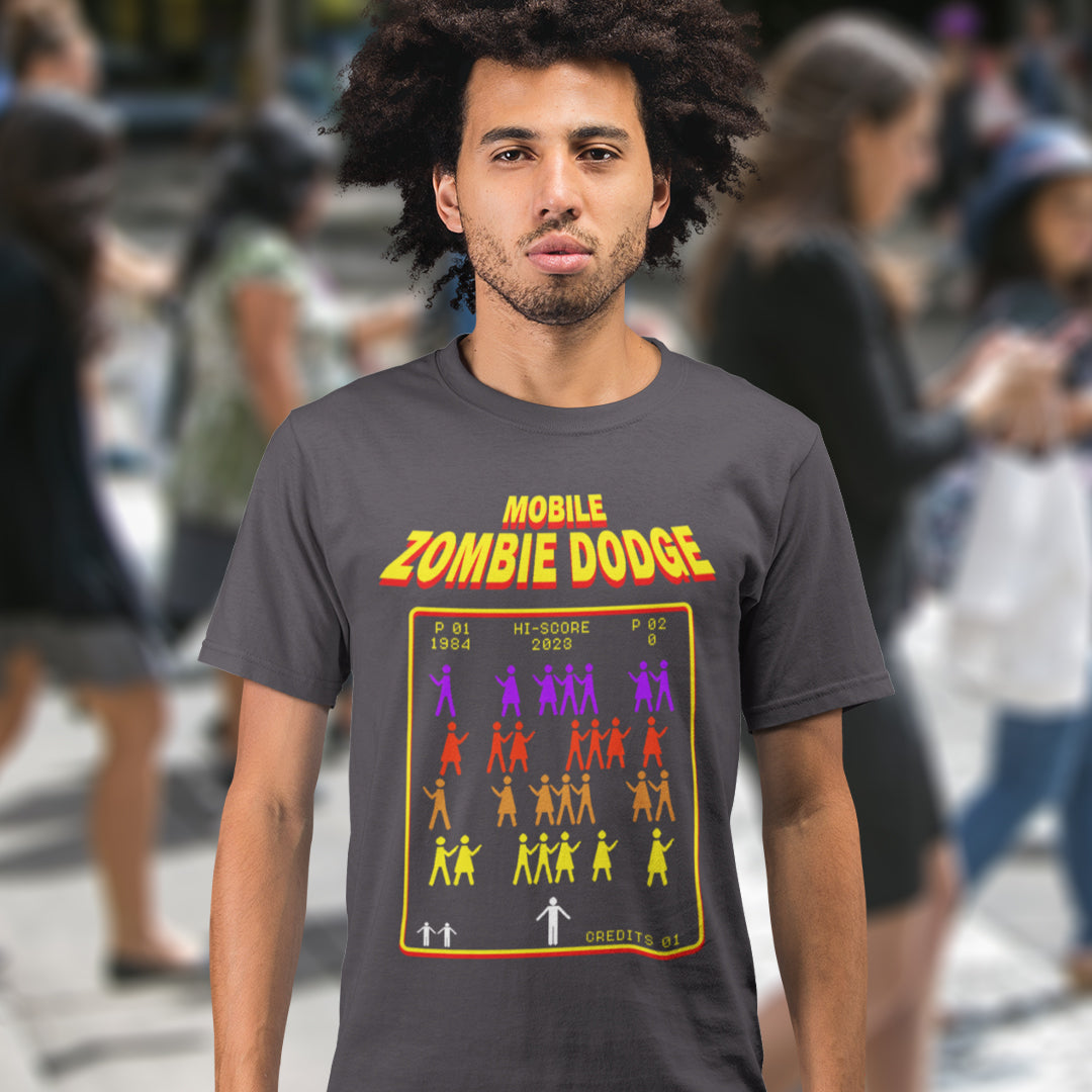 Man wearing a t-shirt with 'Mobile Zombie Dodge' design in an urban setting. A funny gamer t shirt design for anyone who feels they are in a repetitive 80's video game every time they enter a crowded street scene. Welcome to the age of the mobile phone and lack of social awareness. Made from 100% organic ring-spun cotton, this unisex gamer t shirt is alternative and original. It's high-quality, super comfy, and best of all, eco-friendly.