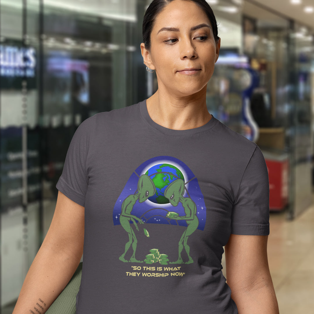 Person wearing a t-shirt with an alien design and text in a store setting. This funny sci fi t shirt is for alien lovers and anti capitalist, and depicts the disappointment of a civilisation now overly obsessed with money and greed. Is it any wonder the aliens have given up on us. Made from 100% organic ring-spun cotton, this anti capitalist t shirt is unisex, high-quality, super comfy, and best of all, eco-friendly.