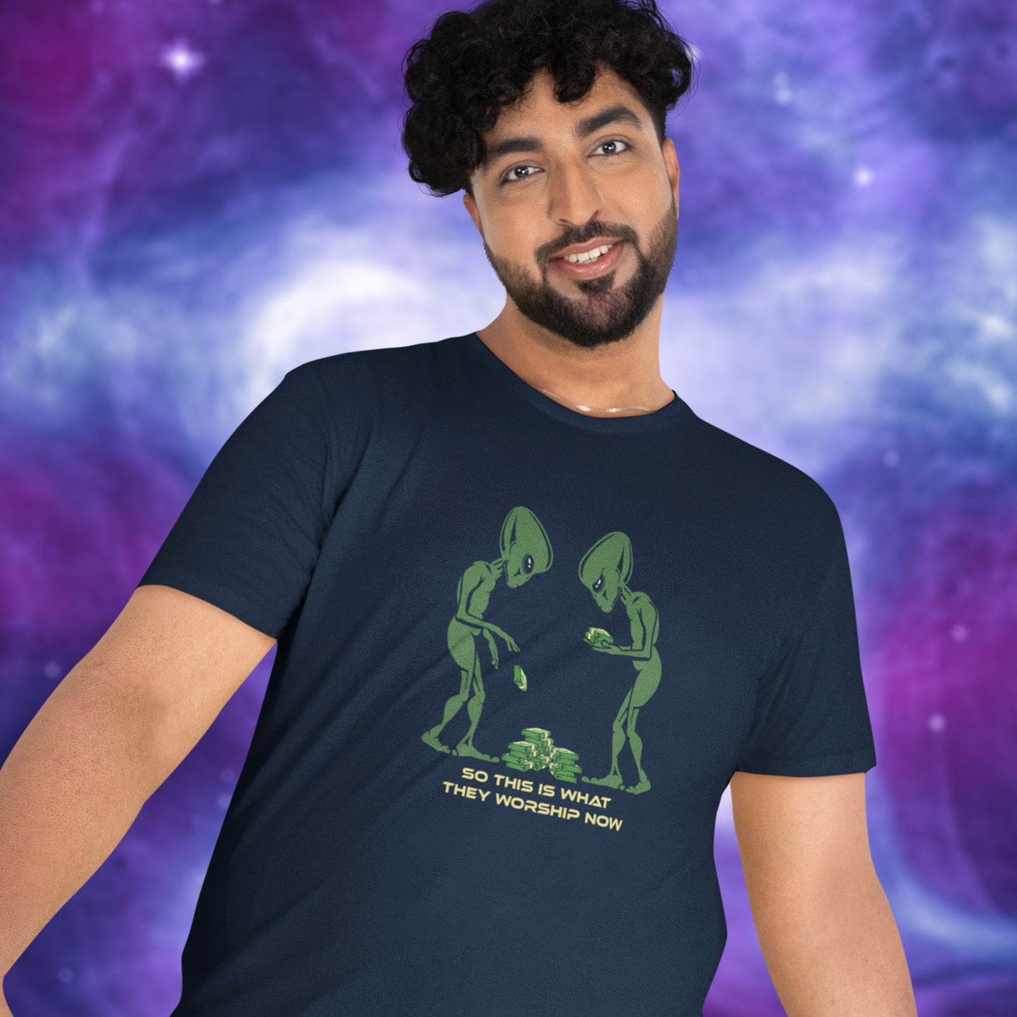 Man wearing a navy blue t-shirt with green alien design and text against a purple and blue gradient background. This funny anti-capitalism t-shirt is for alien lovers, and depicts the disappointment of a civilisation now overly obsessed with money and greed. Is it any wonder the aliens have given up on us. Made from 100% organic ring-spun cotton, this social awareness/alien t-shirt is unisex, high-quality, super comfy, and best of all, eco-friendly.
