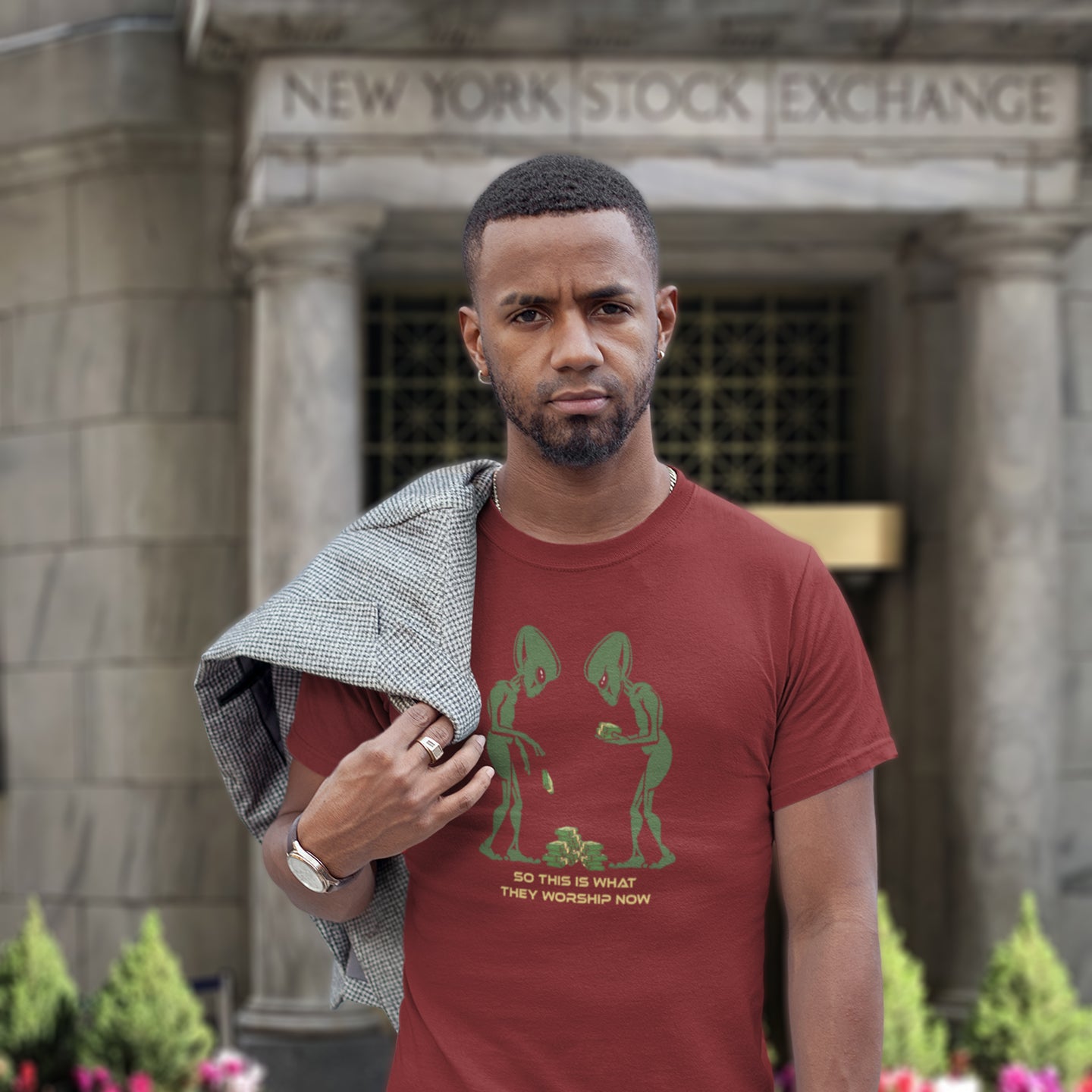 Man wearing a red t-shirt with green graphics in front of the New York Stock Exchange. This funny anti-capitalism t-shirt is for alien lovers, and depicts the disappointment of a civilisation now overly obsessed with money and greed. Is it any wonder the aliens have given up on us. Made from 100% organic ring-spun cotton, this social awareness/alien t-shirt is unisex, high-quality, super comfy, and best of all, eco-friendly.