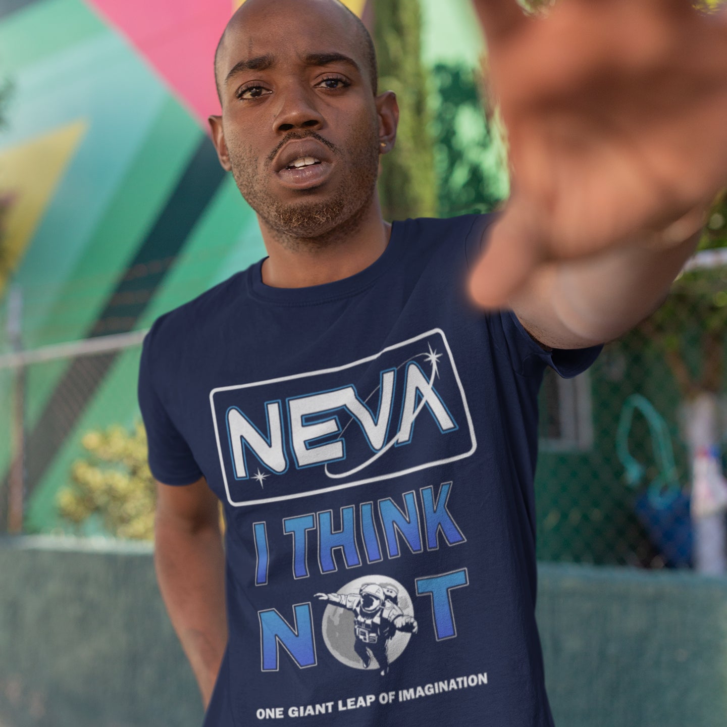 Man wearing a blue t-shirt with text and graphics, pointing forward with a colourful background. A conspiracy theory t-shirt design for all you die hard moon landing sceptics out there. Made from 100% organic ring-spun cotton, this witty conspiracy theory t-shirt is unisex, high-quality, super comfy, and best of all, eco-friendly.