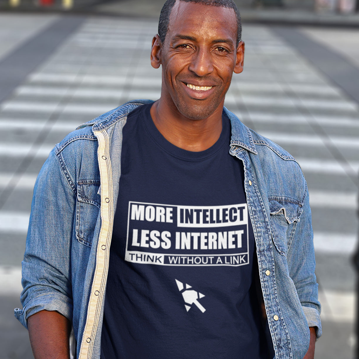 Man wearing a French navy t-shirt with text and a denim jacket on a blurred street background. A social issues t shirt design exposing how lazy the internet has made our thought process. Think without a link and keep your brain alive, or end up just believing what you're told. Made from 100% organic ring-spun cotton, this intelligent t shirt design is unisex, high-quality, super comfy, and best of all, eco-friendly.