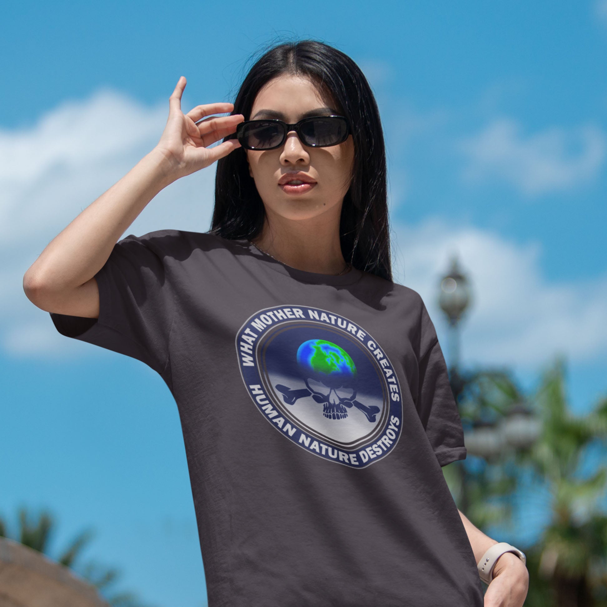 Person wearing a t-shirt with a graphic design outdoors against a blue sky. Mother nature vs. human nature. Climate concern at it's rawest. A design for all eco warriors who would love to save the planet. Made from 100% organic ring-spun cotton, this environmental awareness t-shirt is unisex, high-quality, super comfy, and best of all, eco-friendly.