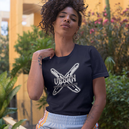 A woman with her hair tied up and scratching her neck , wearing a French navy blue short sleeved crew neck t-shirt with a graphic of two crossed vegetable peelers and the text "VEGAN, NATURAL BORN PEELER" printed over the top.
