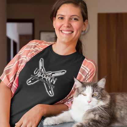 A smiling woman stood next to a cat sat on a surface, wearing a black crew neck t-shirt with a graphic of two crossed vegetable peelers and the text "VEGAN, NATURAL BORN PEELER" printed over the top.